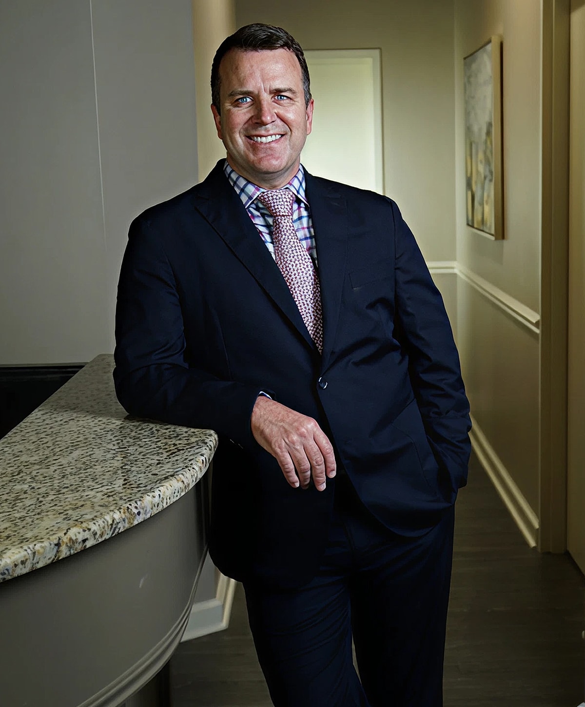 Man in suit leaning against a counter