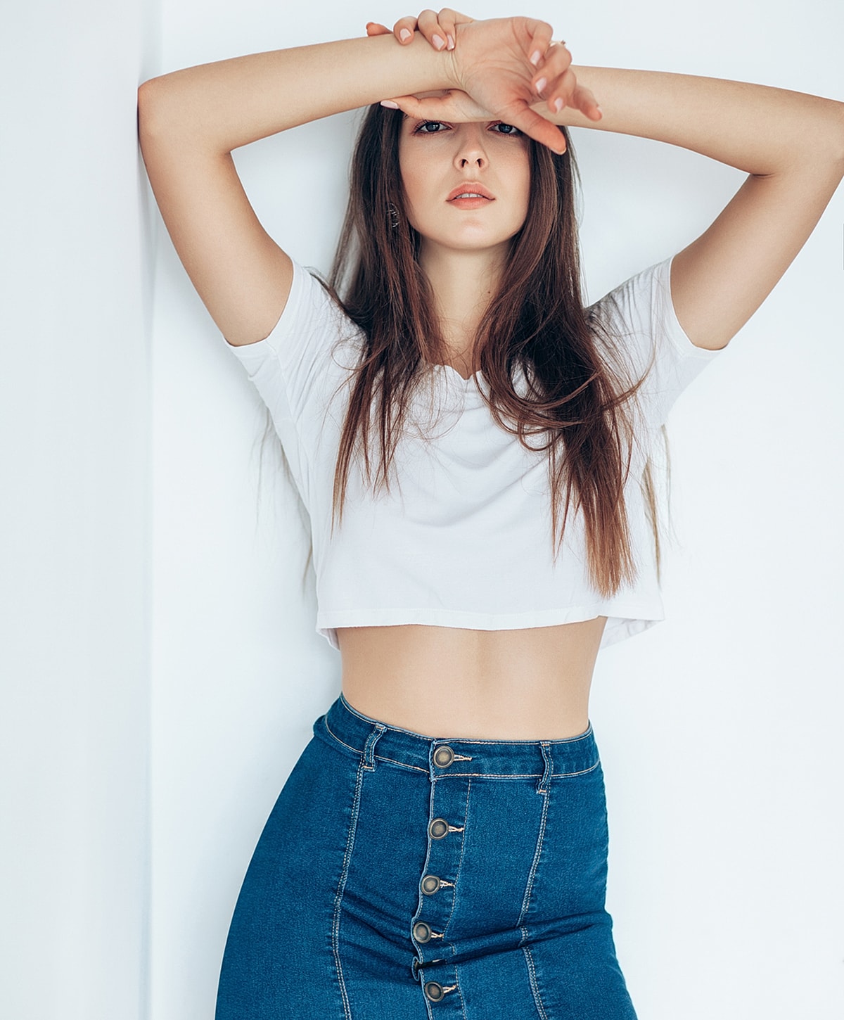 Woman in crop top and denim skirt posing.