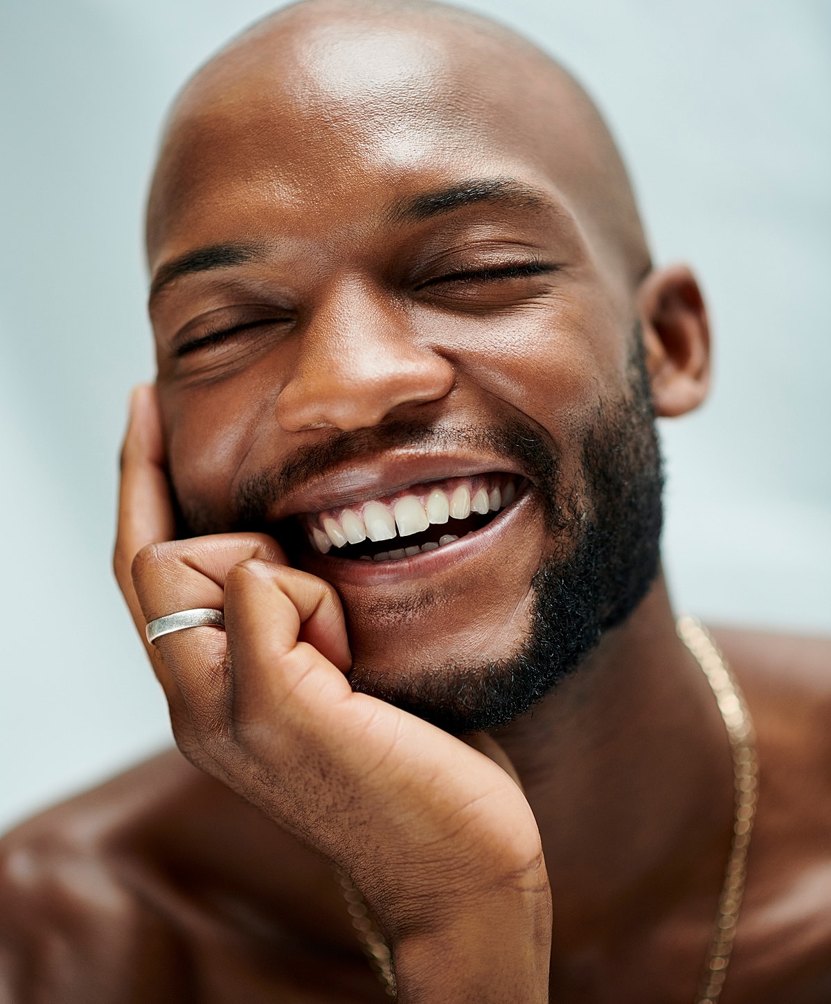 Smiling man with beard resting his chin.