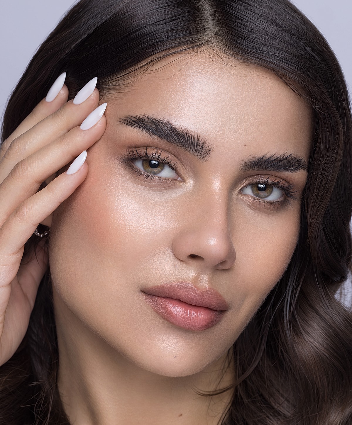 Close-up of a woman’s face and manicure.