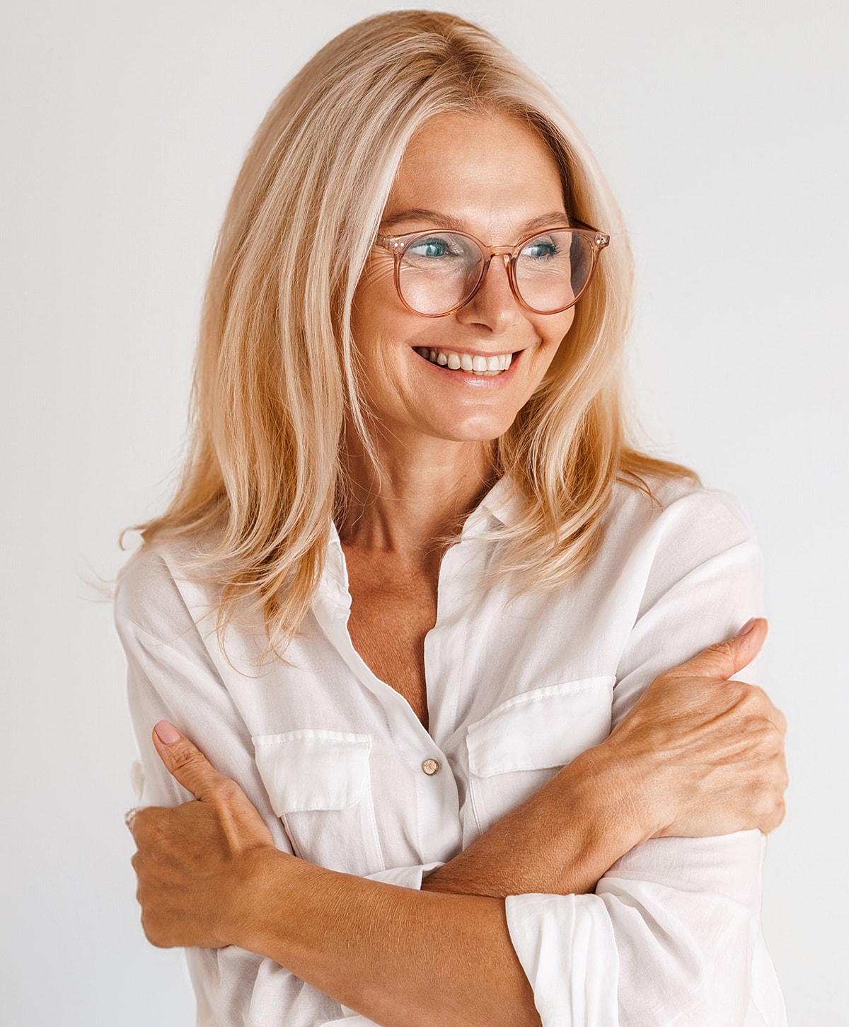 Smiling woman with glasses, arms crossed, white shirt.