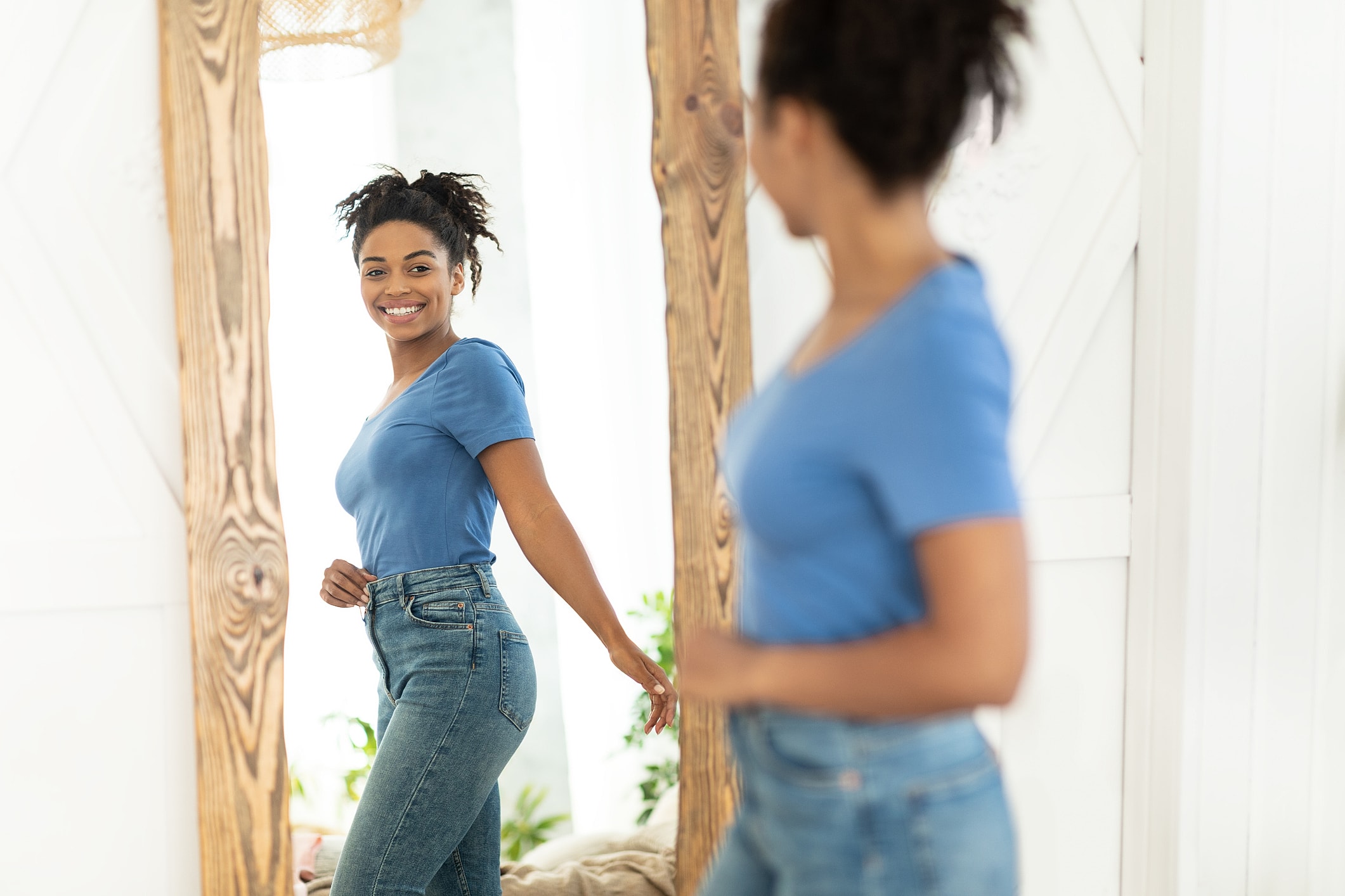 Smiling woman admiring reflection in mirror.