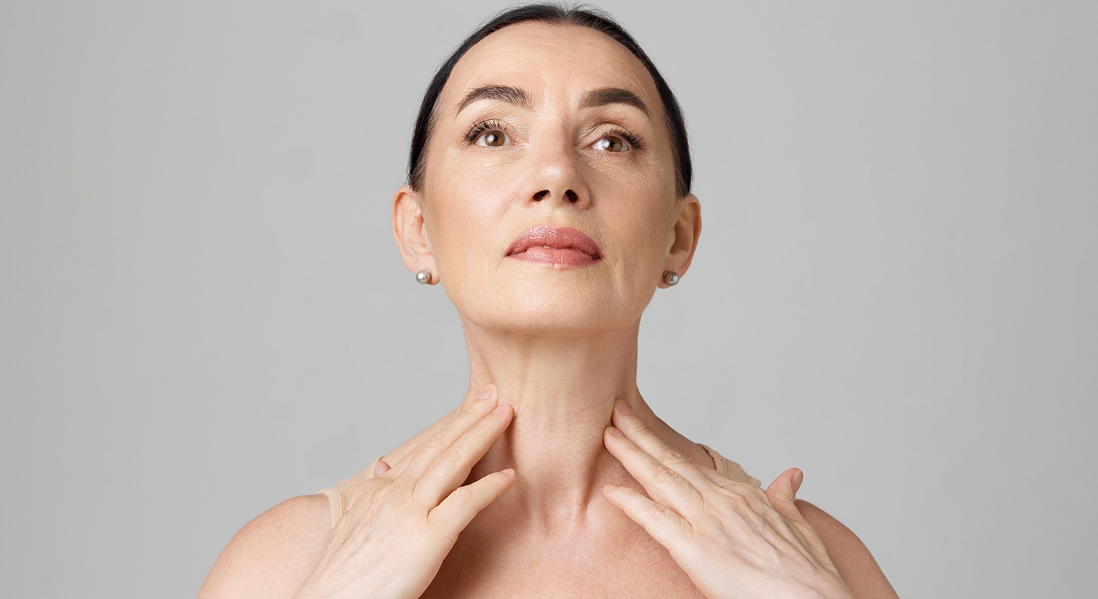 Woman applying skincare to her neck and jawline.