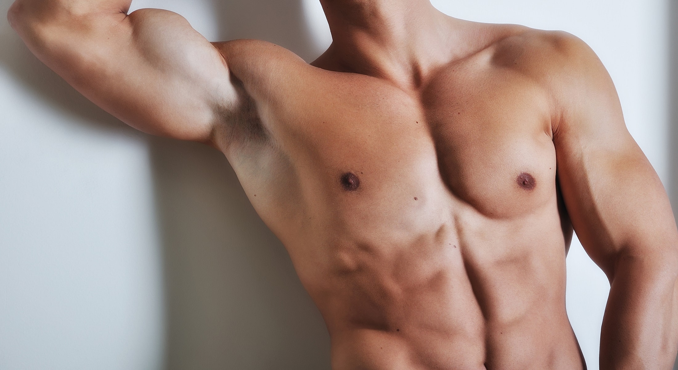 Male torso with defined muscles against a wall.