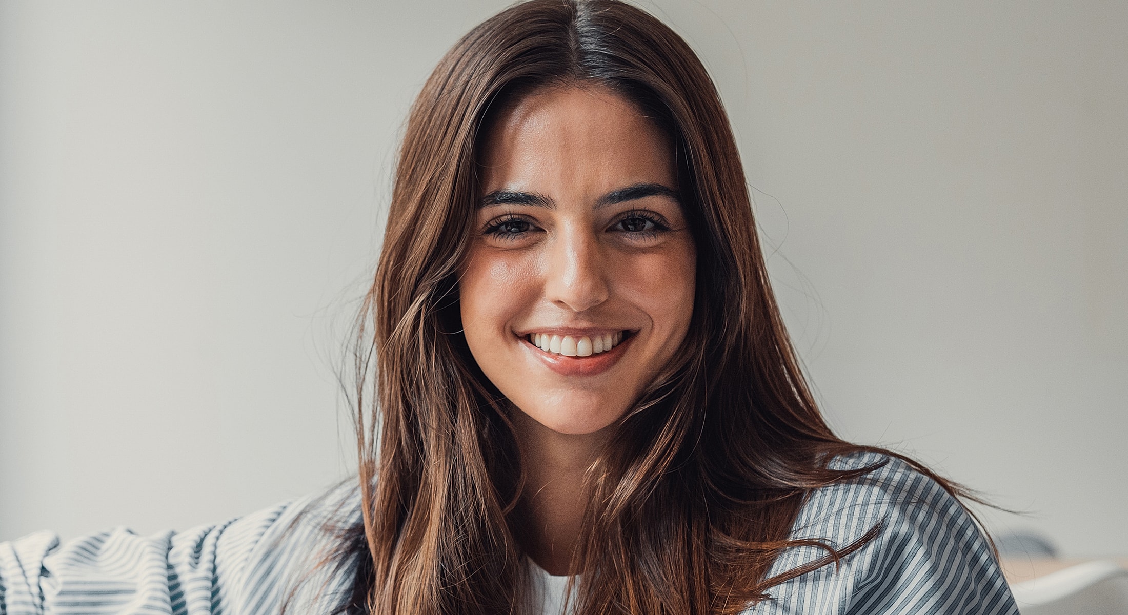Smiling woman with long brown hair indoors.